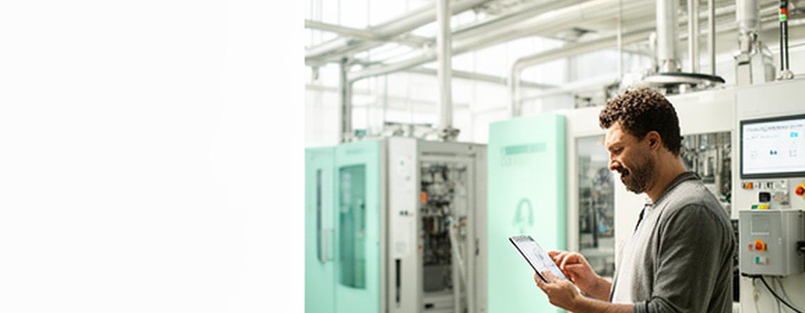 Resource manager reviewing energy and materials data beside production equipment in a bright UK facility