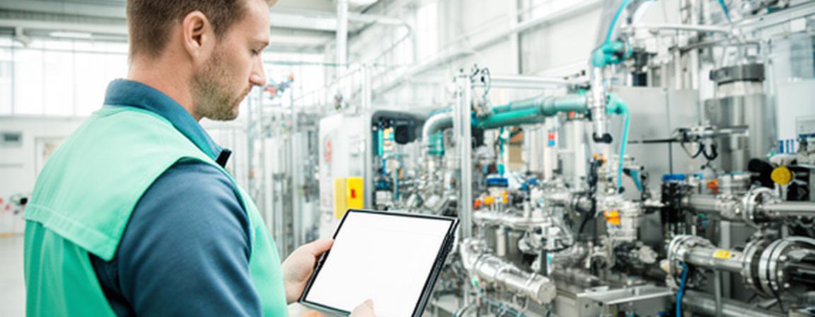 Operations manager reviewing resource flow data beside equipment in a bright Leeds manufacturing facility